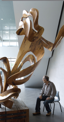 David Fels sits under his sculpture “Sailing Through Time” carved from a centuries-old oak. Photo by Tony Fouhse.