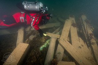 Parks Canada underwater archaeologist Filippo Ronca measures the diameter of a cannon found with the wreckage of the HMS Erebus. Photo by Thierry Boyer, Parks Canada.